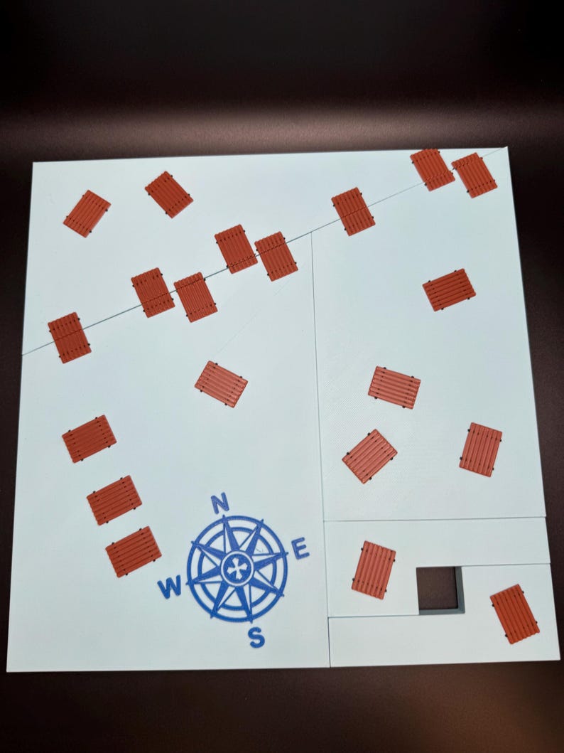 May include: A white board game with a blue compass rose and scattered red wooden bridge pieces. A thin gray line runs across the board. The game board is divided into sections.