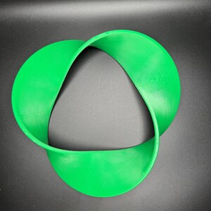 May include: A bright green plastic three-dimensional object shaped like a Mobius strip.