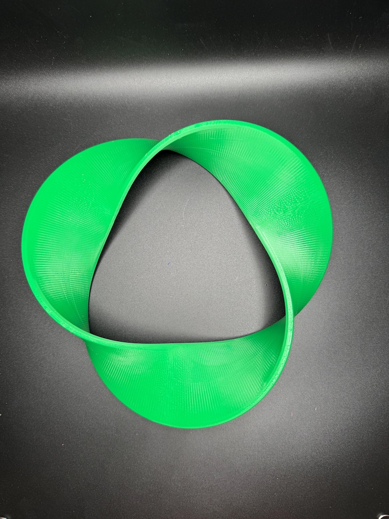 May include: A bright green plastic three-dimensional object shaped like a Mobius strip.