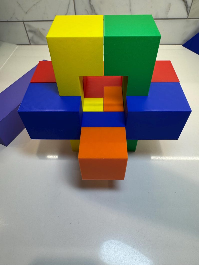May include: A colorful wooden puzzle with six blocks in red, blue, yellow, green, and orange. The blocks are arranged in a complex pattern, creating a three-dimensional shape.
