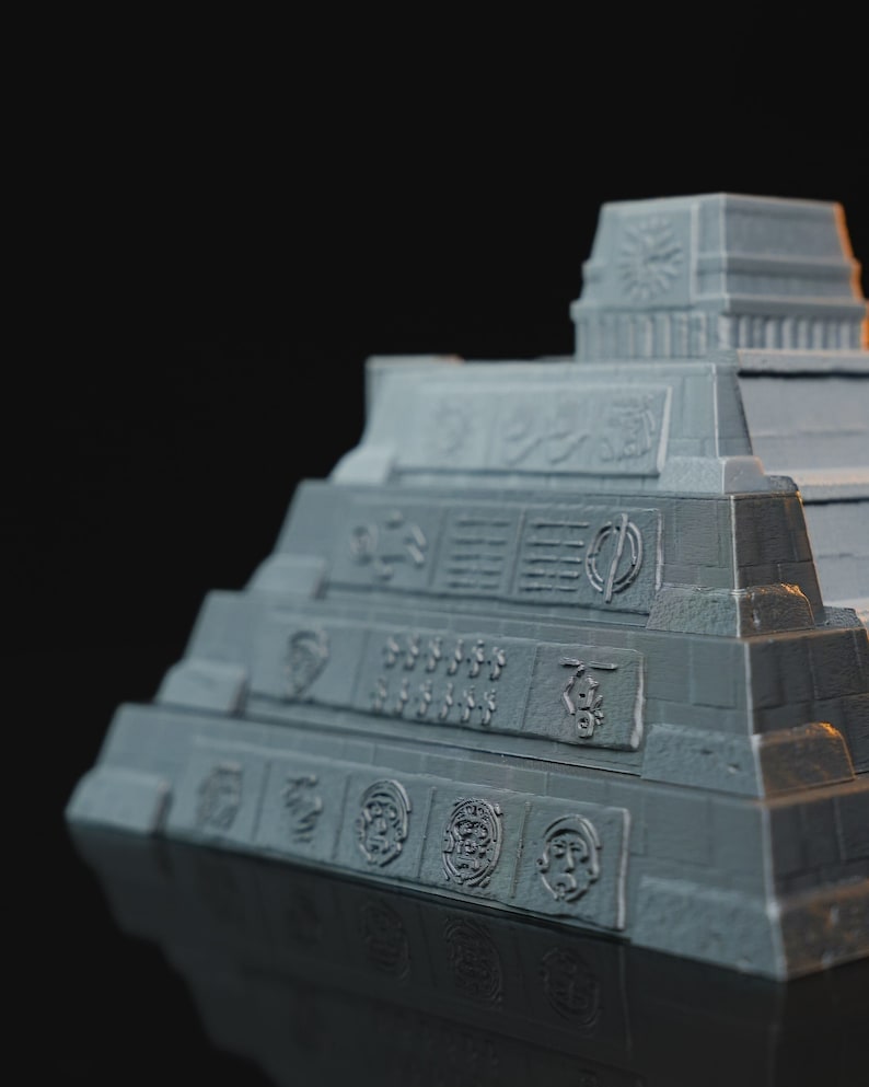 May include: A gray 3D printed model of a Mayan pyramid with intricate details and carvings. The pyramid has multiple levels and a flat top with a small structure on it.