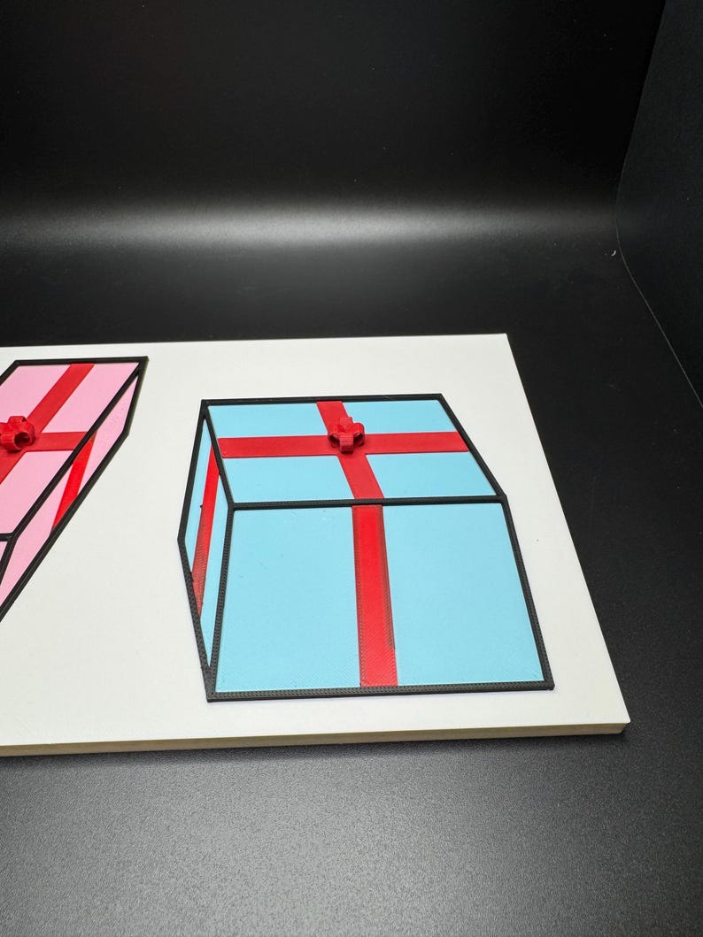 May include: A light blue gift box with a red ribbon and bow, and a pink gift box with a red ribbon and bow. Both boxes have black outlines and are on a white surface.
