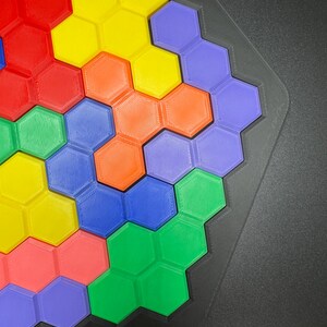 May include: A colorful hexagonal puzzle with pieces in shades of red, orange, yellow, green, blue, and purple. The puzzle is assembled in a honeycomb pattern.