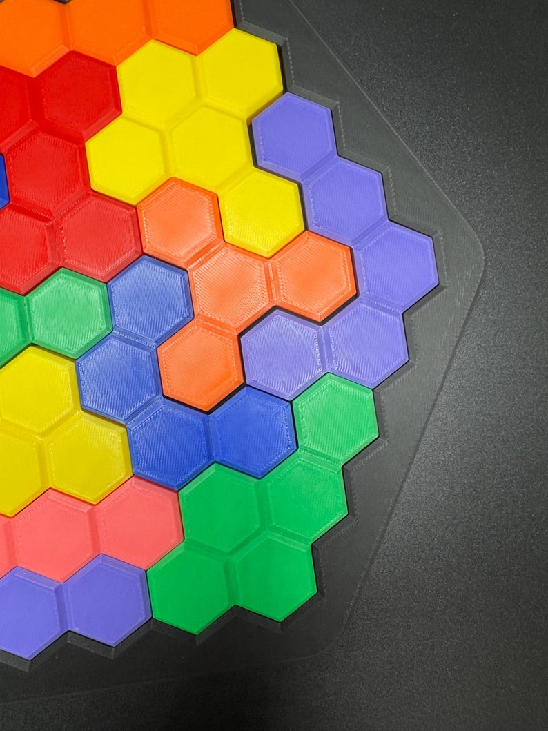 May include: A colorful hexagonal puzzle with pieces in shades of red, orange, yellow, green, blue, and purple. The puzzle is assembled in a honeycomb pattern.