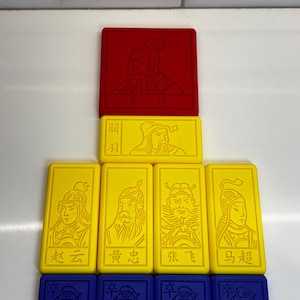 May include: A set of nine colorful game tiles featuring Chinese characters and illustrations. The tiles are arranged in a pyramid shape, with a red tile at the top, followed by two yellow tiles, and then four yellow tiles, and finally four blue tiles at the bottom.