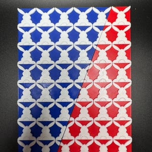 May include: A close-up of a 3D printed tile pattern with white bunny silhouettes on a blue background on the left side of the image and a red background on the right side of the image. The bottom of the image shows a row of tiles in green, yellow, and orange.