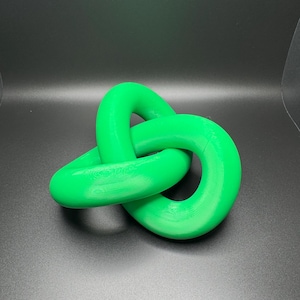 May include: A bright green, three-dimensional knot sculpture. The knot is made of a smooth, plastic material and is shaped like a figure eight.