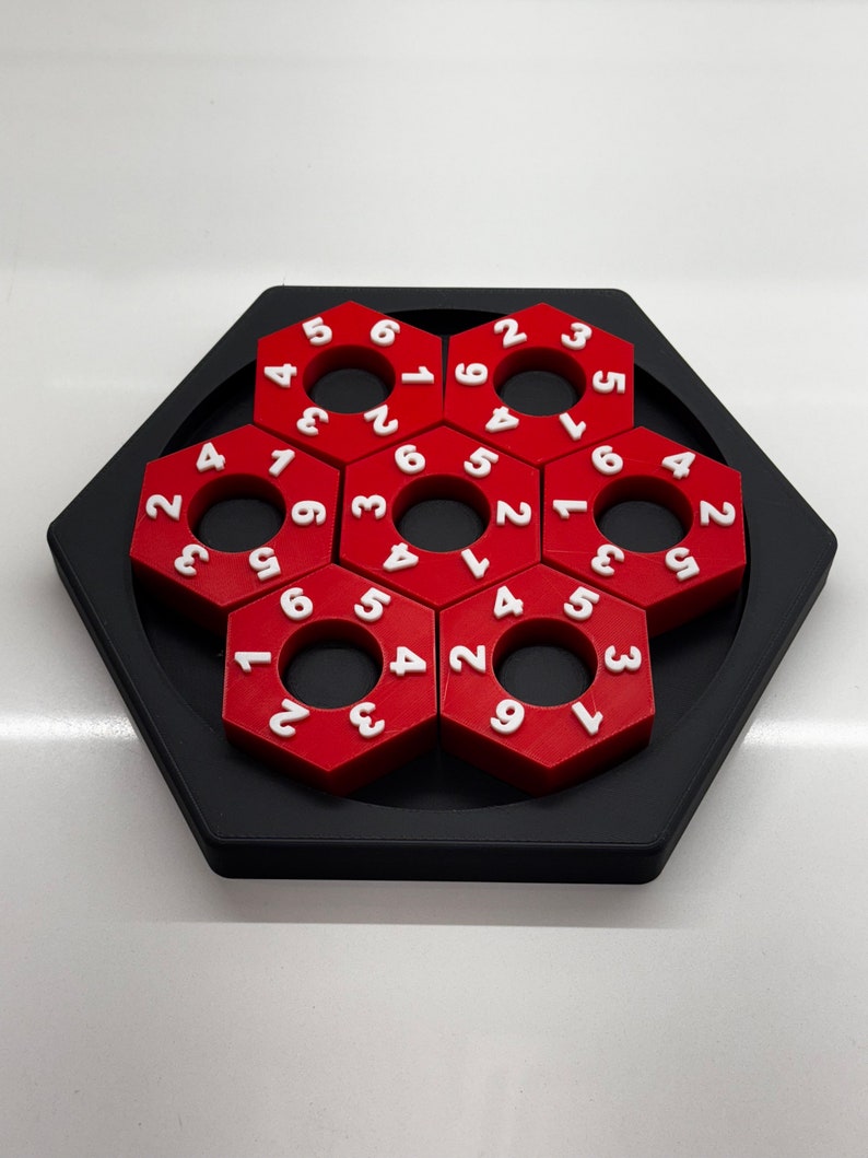 May include: A red hexagonal puzzle with white numbers on each piece. The puzzle is made up of six pieces that fit together to form a larger hexagon.