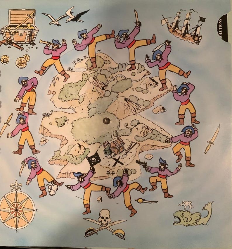 May include: A colorful illustration of a pirate-themed map. The map features cartoon pirates, a treasure chest, a compass, a pirate ship, and a skull and crossbones. The background is light blue.