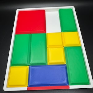 Peut inclure: Un plateau blanc avec un puzzle rouge, vert, jaune et bleu. Les pièces du puzzle sont disposées en grille.