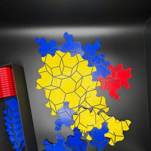 May include: A puzzle with blue, yellow, and red pieces. The pieces are arranged in a pattern that resembles a flower. The puzzle is on a black surface.