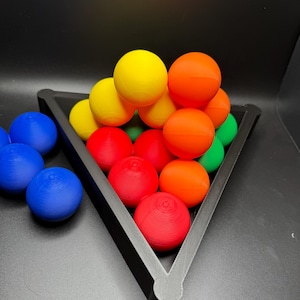 Peut inclure: Un support triangulaire noir contient une pyramide de boules color&eacute;es. Les boules sont rouges, orange, jaunes, vertes et bleues. Le support est sur une surface noire.