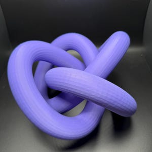 May include: A purple 3D printed knot sculpture. The knot is made of smooth, rounded, interlocking loops.