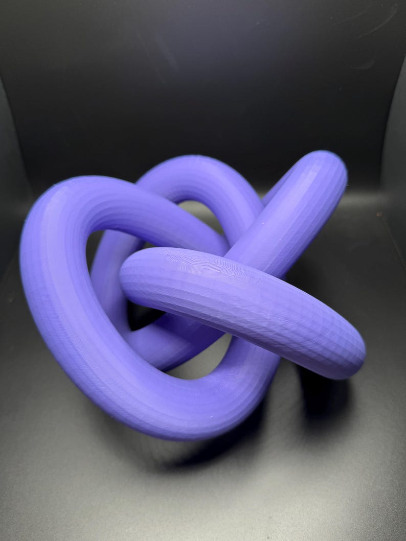 May include: A purple 3D printed knot sculpture. The knot is made of smooth, rounded, interlocking loops.