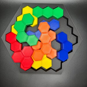 May include: A hexagonal puzzle with six different colored pieces. The pieces are arranged in a spiral pattern, with the colors red, orange, yellow, green, blue, and purple. The puzzle is made of plastic and is designed to be challenging and fun.