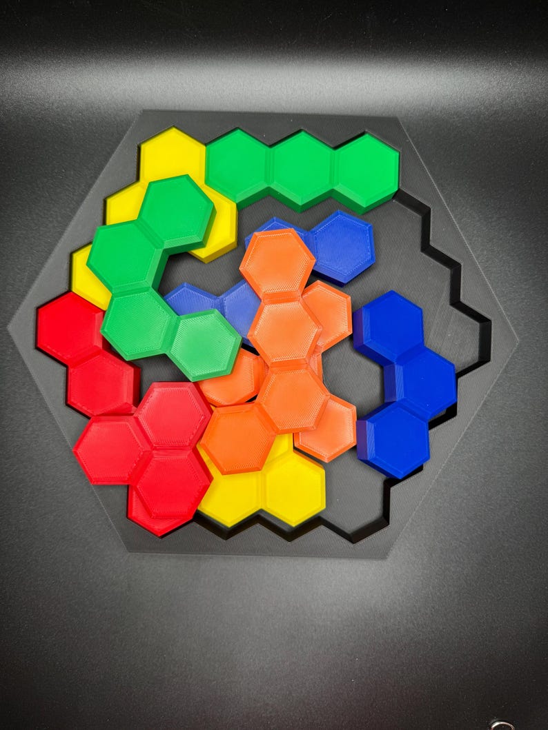 May include: A hexagonal puzzle with six different colored pieces. The pieces are arranged in a spiral pattern, with the colors red, orange, yellow, green, blue, and purple. The puzzle is made of plastic and is designed to be challenging and fun.