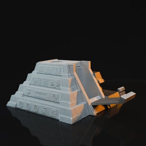 May include: A white 3D printed model of a Mayan pyramid with a ramp leading up to the top. The pyramid is decorated with intricate carvings and symbols.