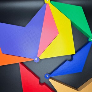 Peut inclure: Un puzzle g&eacute;om&eacute;trique color&eacute; compos&eacute; de diverses formes et couleurs, notamment le rouge, le bleu, le jaune, le vert et l'orange. Les pi&egrave;ces sont reli&eacute;es par de petites attaches m&eacute;talliques, cr&eacute;ant un design visuellement attrayant. Le puzzle est pos&eacute; sur un fond sombre.