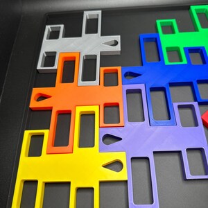 K&ouml;nnte beinhalten: Eine Sammlung farbenfroher, ineinandergreifender Puzzleteile in verschiedenen Formen und Gr&ouml;&szlig;en. Die Teile sind in den Farben Gelb, Orange, Grau, Gr&uuml;n, Blau und Lila gehalten. Die Puzzleteile sind auf einer schwarzen Oberfl&auml;che angeordnet.