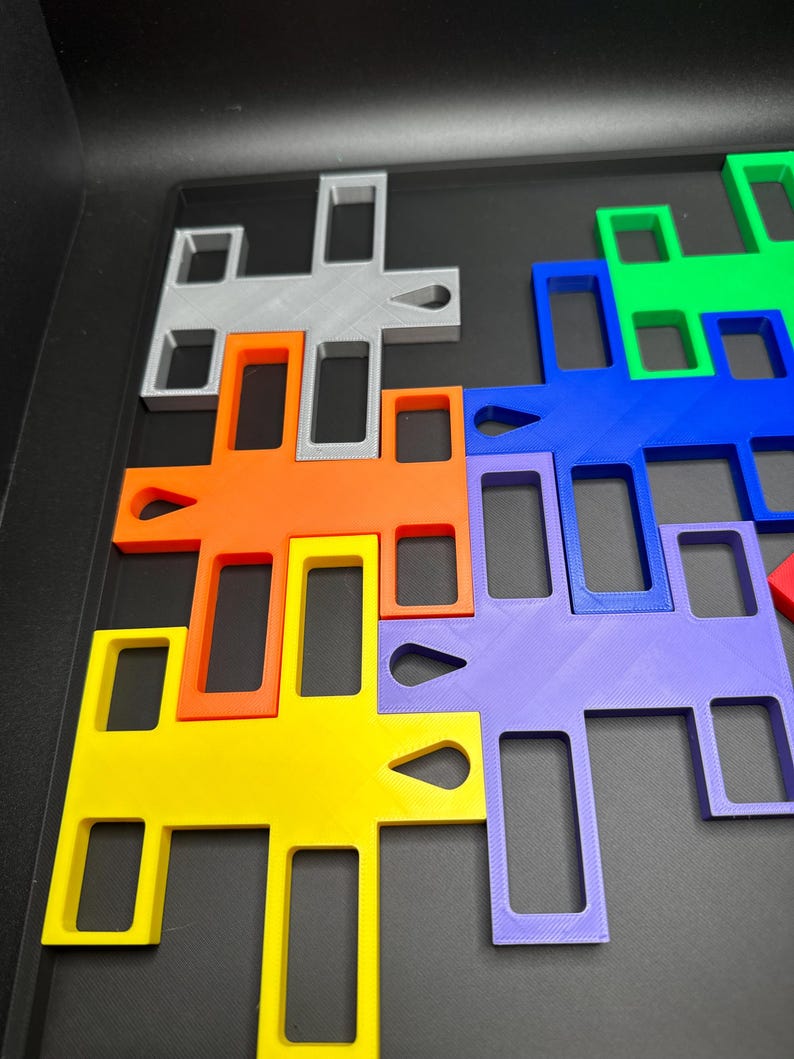 K&ouml;nnte beinhalten: Eine Sammlung farbenfroher, ineinandergreifender Puzzleteile in verschiedenen Formen und Gr&ouml;&szlig;en. Die Teile sind in den Farben Gelb, Orange, Grau, Gr&uuml;n, Blau und Lila gehalten. Die Puzzleteile sind auf einer schwarzen Oberfl&auml;che angeordnet.