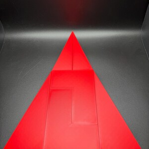 May include: A red triangle made of folded paper. The triangle is divided into smaller triangles and rectangles.
