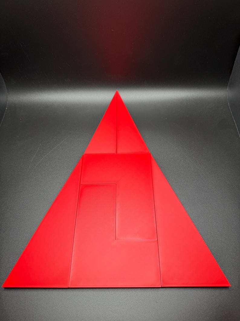 May include: A red triangle made of folded paper. The triangle is divided into smaller triangles and rectangles.