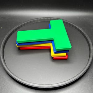 Op de afbeelding: Vier T-vormige gereedschappen van plastic, gestapeld op elkaar. De bovenste tool is groen, de volgende is blauw, de volgende is geel en de onderste tool is rood.
