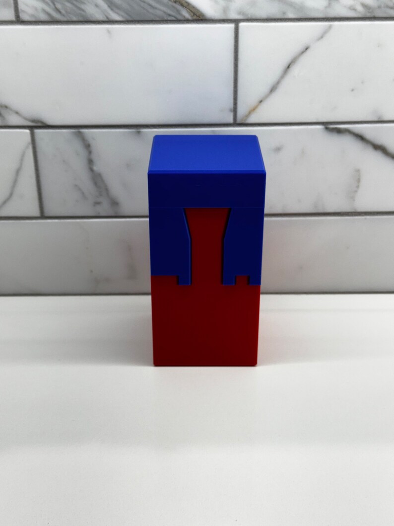 May include: A red and blue box with a unique design. The top of the box is blue and the bottom is red. The box has a cutout in the middle.