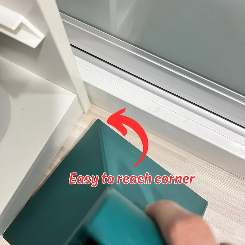 May include: A teal-colored cleaning tool with a triangular head, designed to reach hard-to-clean corners. The tool is positioned in a corner, with a red arrow pointing to the corner and the text "Easy to reach corner".