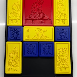 May include: A black tray with nine yellow, red, and blue tiles. Each tile features a different illustration of a person with a unique design. The tiles are arranged in a 3x3 grid. The text on the tiles reads "黄忠", "曹睿", "马超", "関羽", "张云", "张飞".