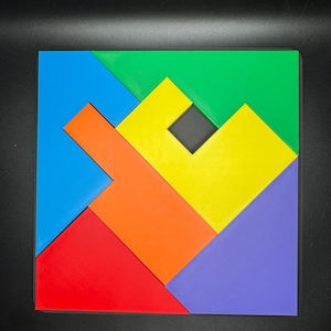 May include: A colorful geometric puzzle with seven pieces in shades of blue, green, yellow, orange, red, and purple. The pieces fit together to form a square shape with a small black square in the center.