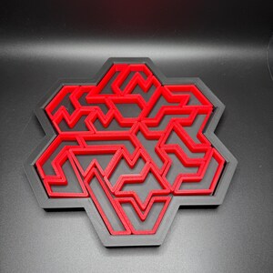 May include: A red 3D printed geometric design with a honeycomb shape. The design is made up of multiple layers of interlocking shapes.