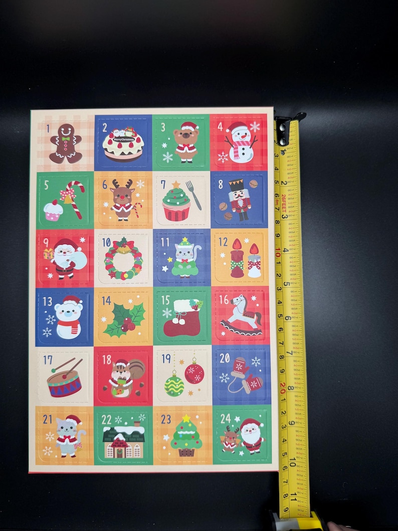 May include: A Christmas advent calendar with 24 colorful squares, each featuring a festive illustration and a number. The calendar is approximately 9 inches tall. The illustrations include a gingerbread man, snowman, and Santa Claus.