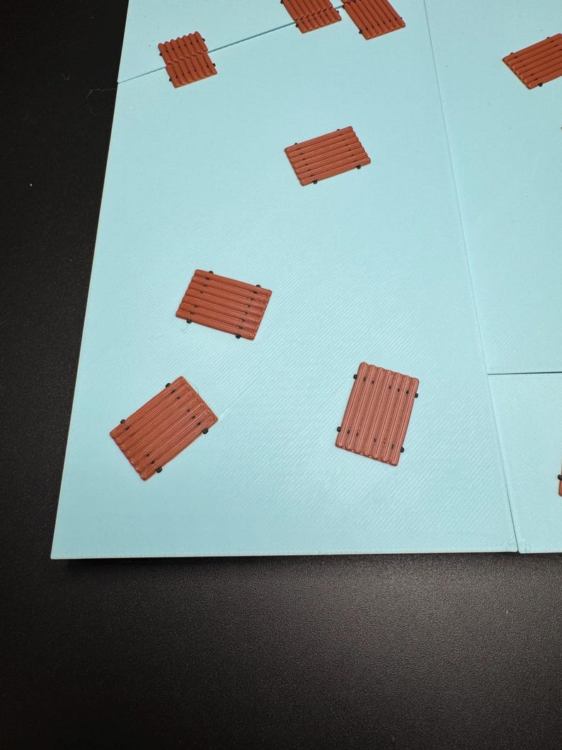 May include: A light blue game board with several small, brown, wooden-looking platforms scattered across its surface. The platforms have a rectangular shape with parallel lines and small black dots.