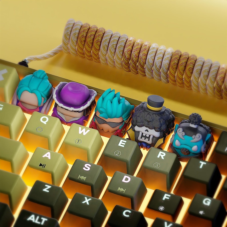 May include: A keyboard with keycaps featuring colorful cartoon characters. The keycaps are on the keys Q, W, E, R, T, A, S, D, F, Z, X, C, and G. The keyboard has a yellow and brown color scheme.
