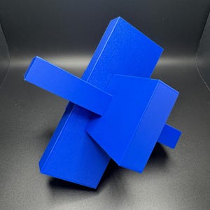 K&ouml;nnte beinhalten: Eine blaue abstrakte Skulptur aus geometrischen Formen. Die Skulptur besteht aus drei rechteckigen Prismen, die &uuml;bereinander gestapelt sind und sich in verschiedenen Winkeln schneiden.