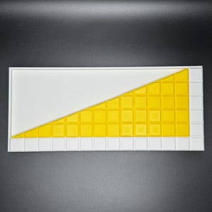 May include: A white tray with a yellow grid pattern in the shape of a triangle. The grid is made up of small squares.
