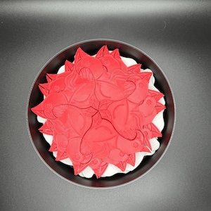 May include: A red 3D printed design of a bird in a circular frame. The design is made up of multiple bird shapes that are layered on top of each other.