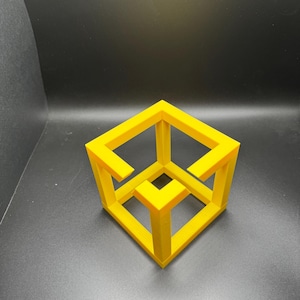 May include: A vibrant yellow impossible cube, a 3D printed optical illusion, is set against a dark backdrop. The cube's design creates an optical paradox, with its edges appearing to defy perspective. A fascinating geometric object.