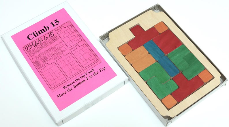May include: A wooden puzzle game called "Climb 15" with a pink instruction card. The game includes a wooden frame with colorful wooden blocks that need to be moved to solve the puzzle.