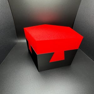May include: A black and red geometric box with a red felt lining. The box is made of wood and has a unique design.
