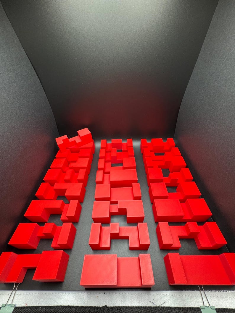 May include: Three red 3D puzzles made of interlocking blocks. Each puzzle is a different shape and size.