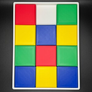 May include: A white tray with 12 colorful square tiles. The tiles are arranged in a 3x4 grid. The colors of the tiles are red, yellow, blue, and green.
