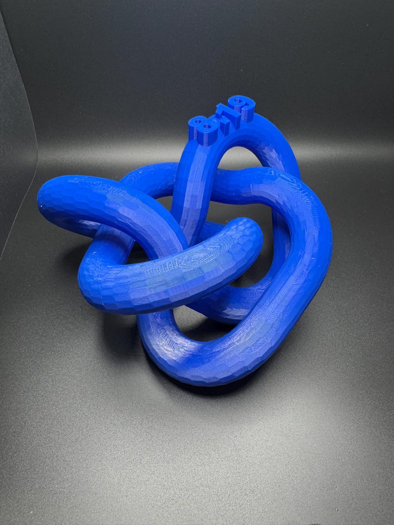 May include: A blue 3D printed knot sculpture with the number "819" printed on the top.