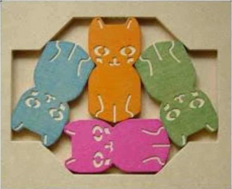 May include: A wooden puzzle featuring six colorful cat-shaped pieces in orange, blue, green, and pink. The puzzle pieces have white facial details and are arranged within a light-colored wooden frame. A fun and engaging toy for children.