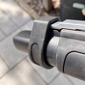 May include: Close-up of a black plastic handlebar with a silver metal lever and a black plastic grip.