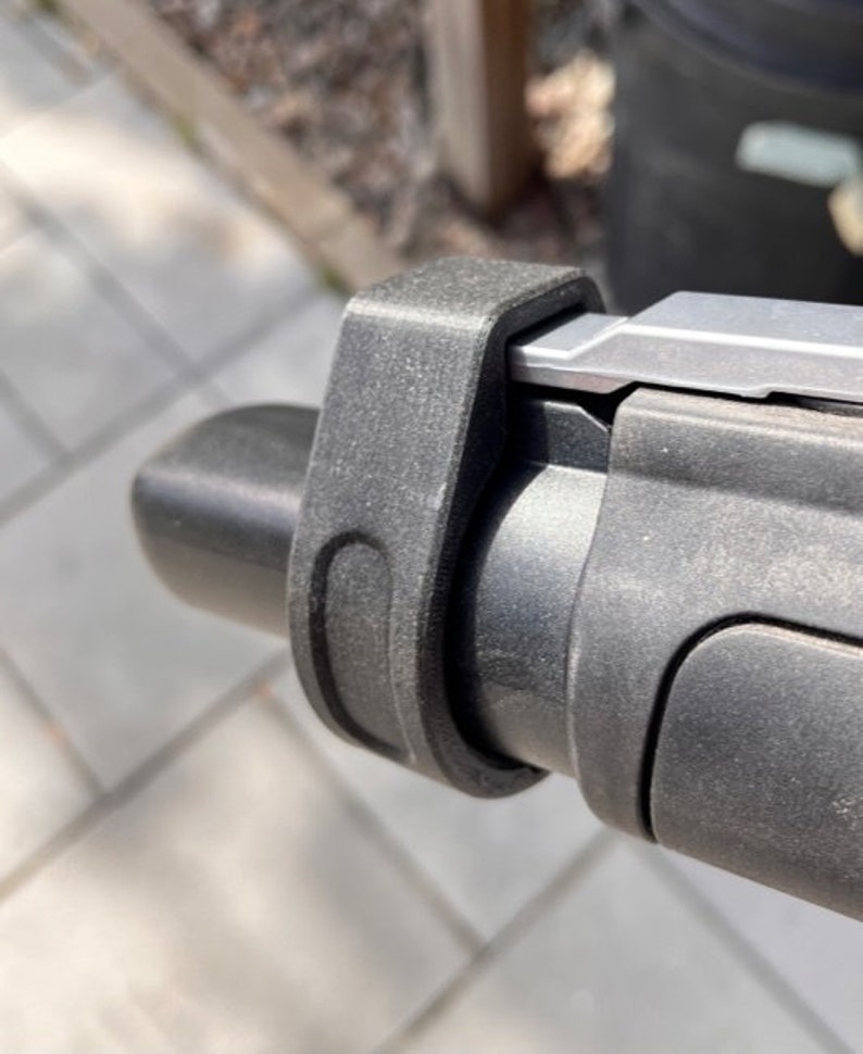 May include: Close-up of a black plastic handlebar with a silver metal lever and a black plastic grip.