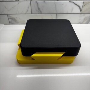 May include: A black and yellow 3D printed box with a lid. The box is made of two pieces that fit together.