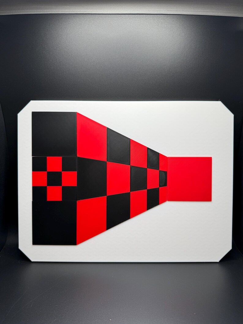 May include: Geometric abstract art piece featuring a white rectangular base with a black and red checkered design. The design includes a red square and a black and red checkered pattern, creating a visually striking composition.