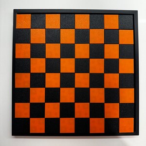 May include: A black and orange checkerboard with a black frame.